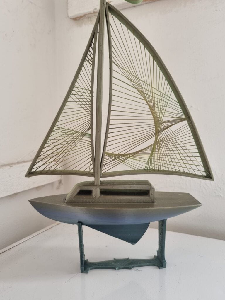 Model sailboat with intricate green sails on display.