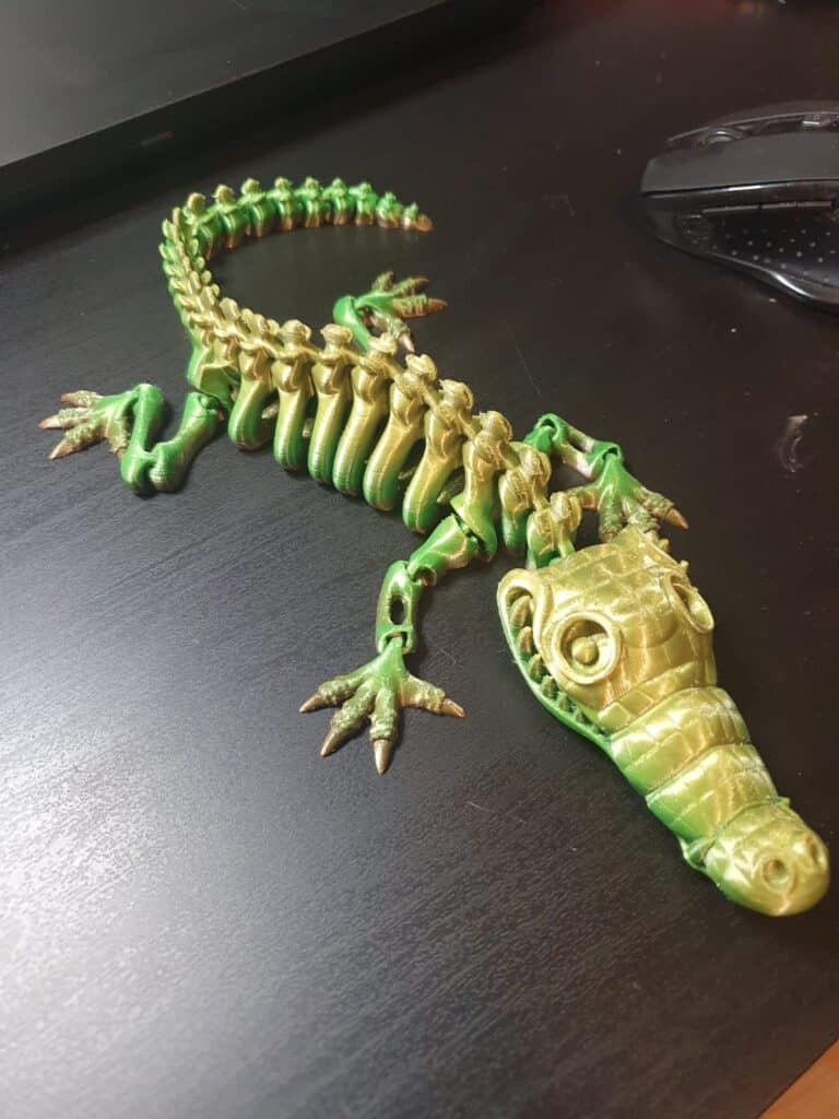 Green and gold crocodile-shaped keychain on a desk.