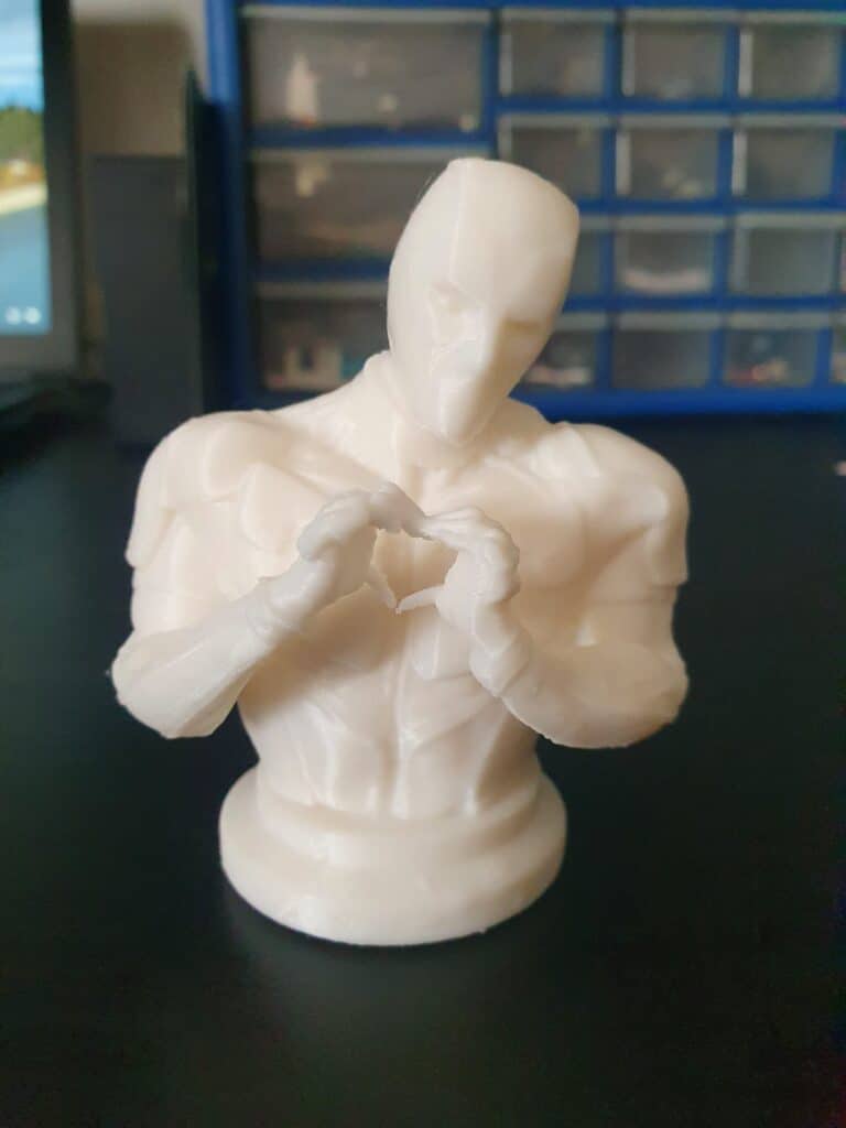 White 3D-printed figure with heart-shaped hand gesture.