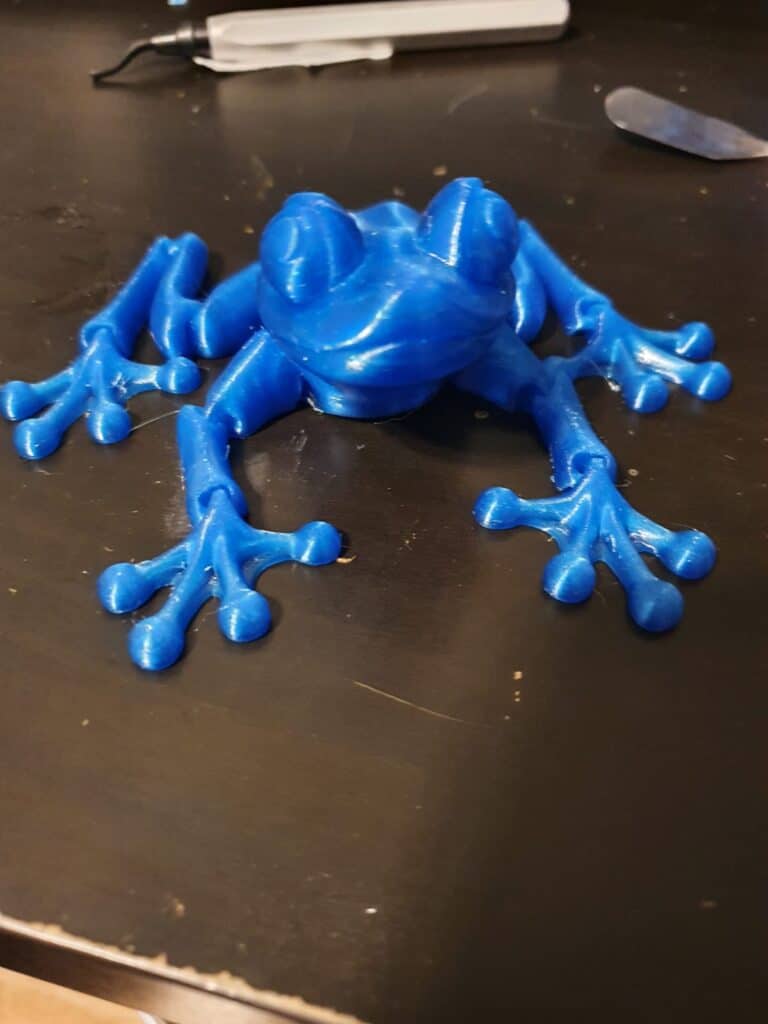 Vibrant blue 3D-printed frog model on black surface.