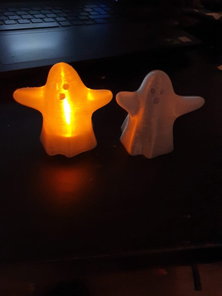 Illuminated ghost figurines on dark desk.