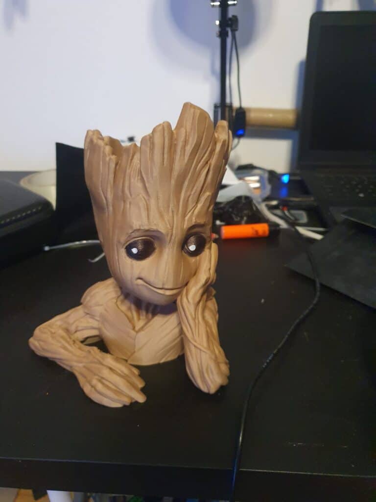 Groot figurine on cluttered desk.