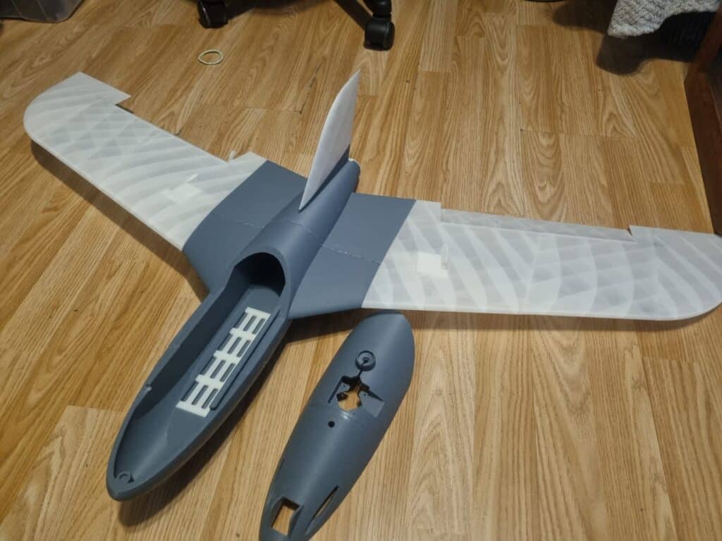 Disassembled grey model airplane on wooden floor.