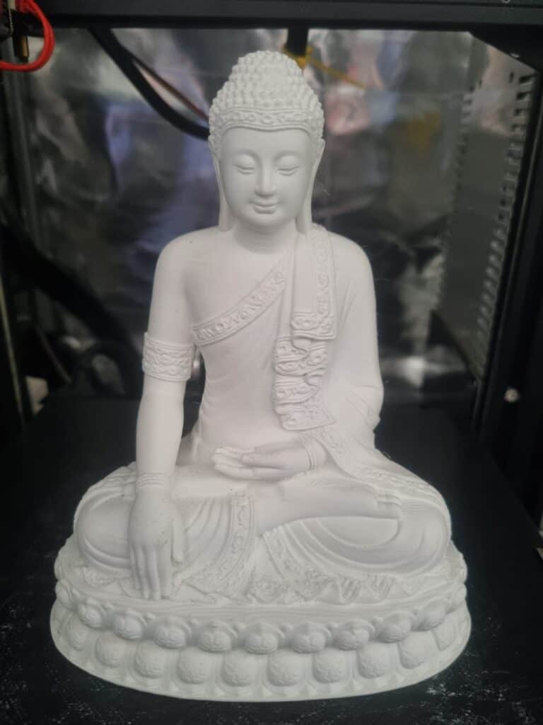 3D printed white Buddha statue in meditative pose.