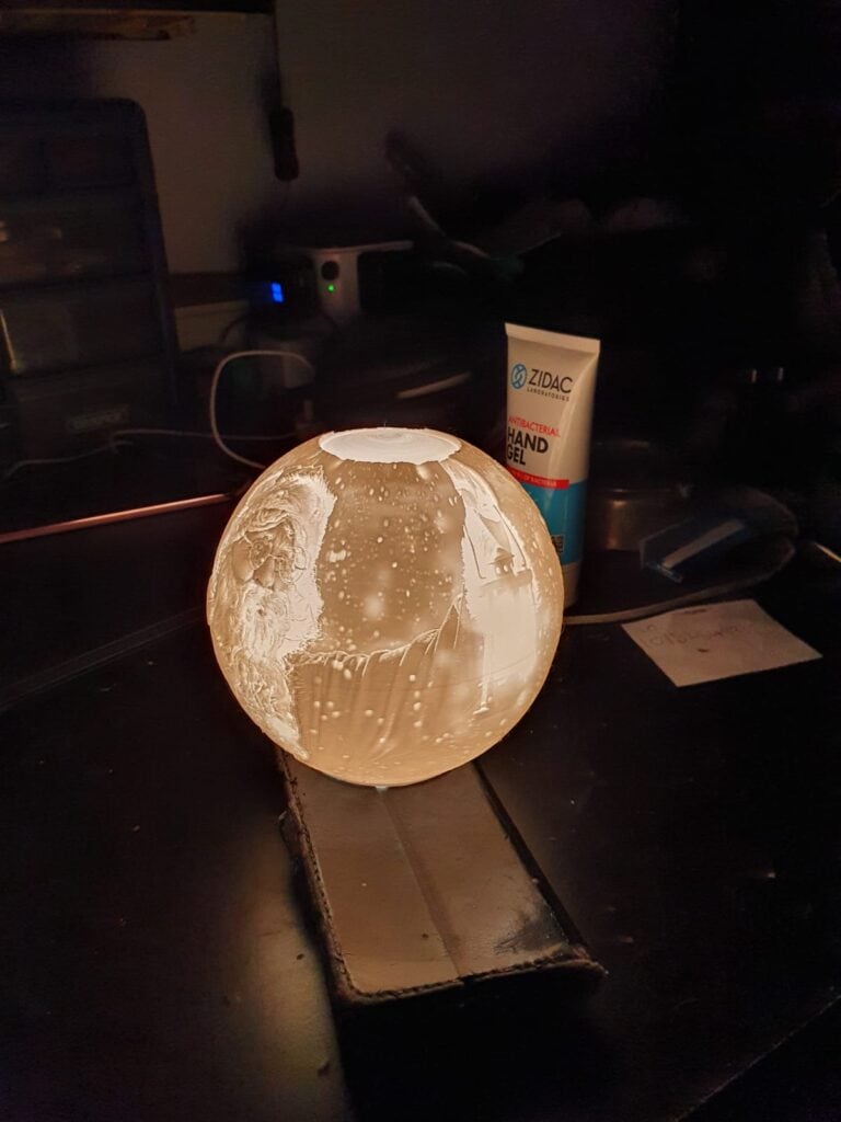 Illuminated globe lamp on desk with hand gel.