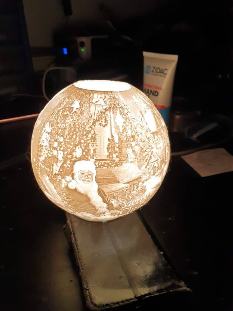 Illuminated Christmas globe depicting Santa and festive scene.