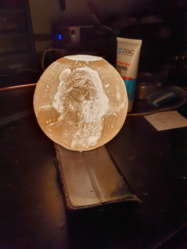 Santa Claus engraving inside illuminated round crystal.