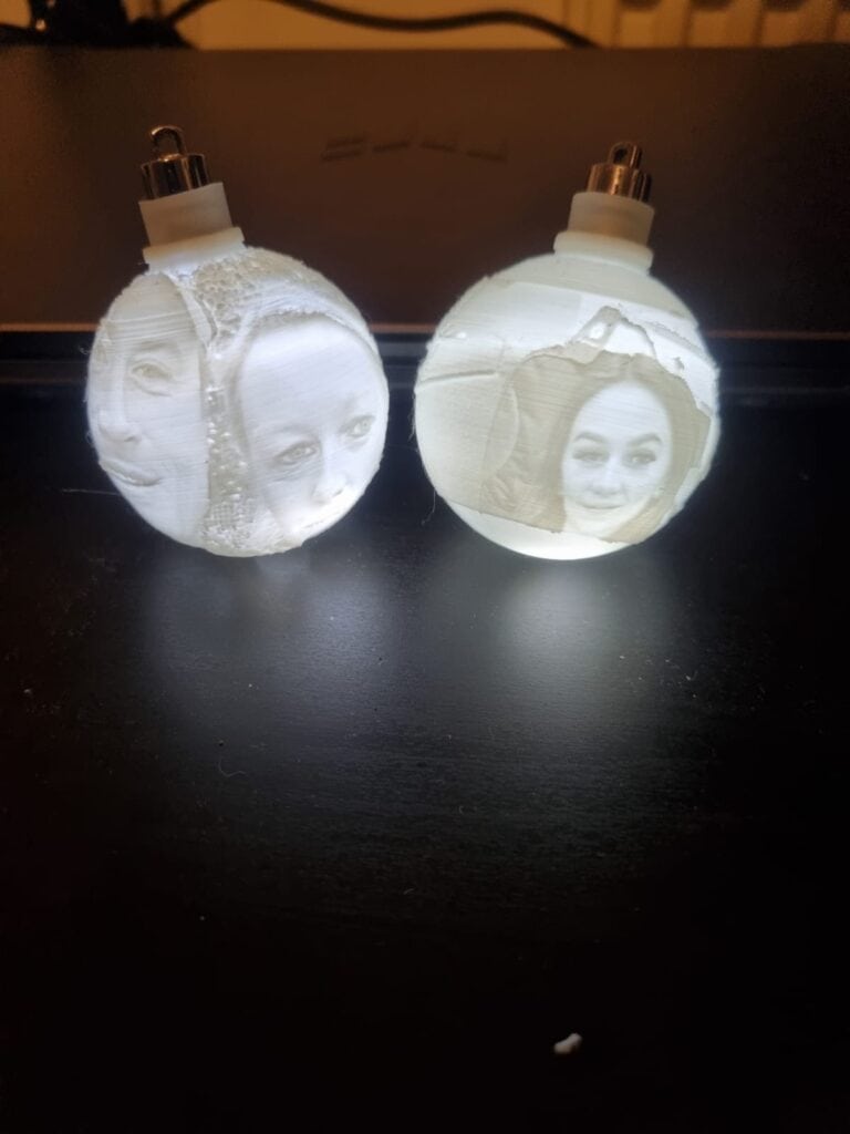 3D-printed face baubles on desk, ambient lighting.