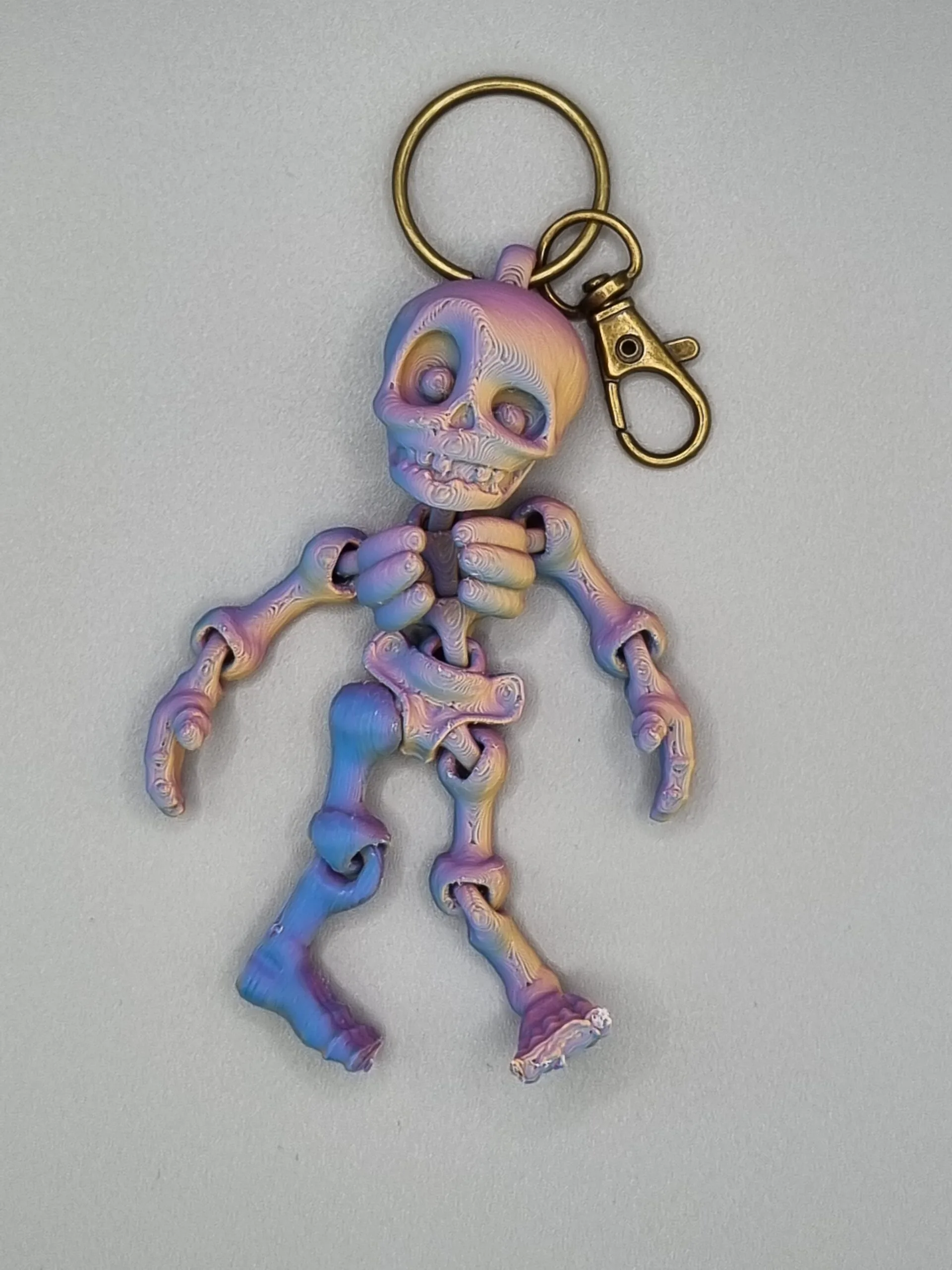 Iridescent skeleton keychain on grey background