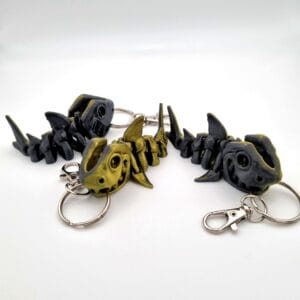 Three articulated skeleton shark keyrings in black and gold