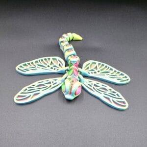 Colourful 3D-printed dragonfly sculpture on dark surface