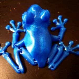 Blue 3D-printed frog figurine on a dark surface
